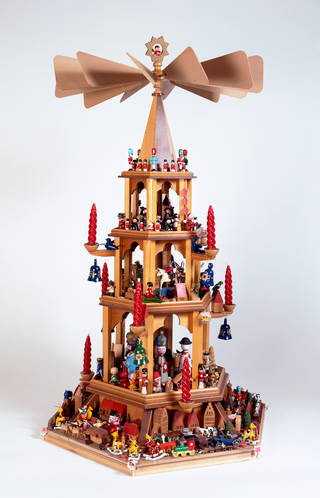 wooden Christmas pyramid with small wooden figurines painted like people on each layer. Red and gold details