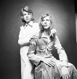 Black and white photograph of two men, David Bowie and Freddie Burretti, one seated and one standing