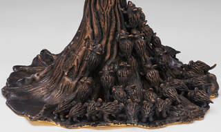 detail of small brown creatures climbing up sculpture that looks like bark