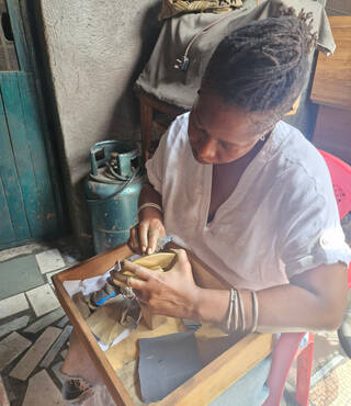 Woman sat at a table looking down at a gold disk that she is working on