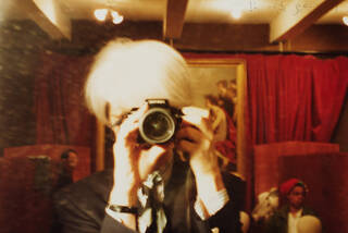 Colour photograph of David Bowie in costume as Andy Warhol in 'Basquiat'