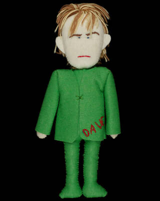 Doll wearing a green suit with the name 'Dave' stitched on the pocket and blonde woollen hair