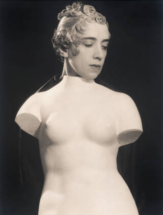 Black and white photograph of a woman's head on a black background with a white sculpture torso as her body