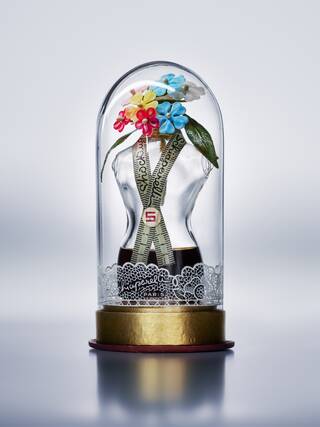 Photograph of a glass dome with a small white bust inside topped with colourful flowers