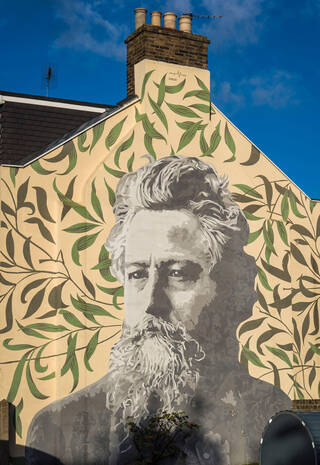 Mural of William Morris painted on the side of a building in greens, yellows and greys