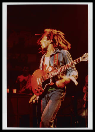 Bob Marley with his guitar on stage