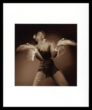 Black and white photo of a woman in sequinned costume with arms in movement