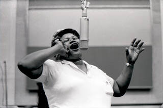 Black and white photo of a woman singing into a microphone