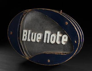 oval metal sign in blue, white and grey with the words Blue Note on it