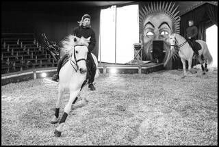 Black and white photo of a woman riding a white horse