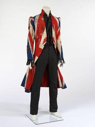 A distressed canvas Union Flag frockcoat with v-neck and high-backed collar, with tears, burn marks, discolourations over it.