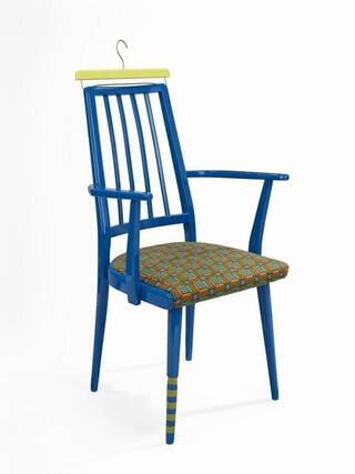 Blue painted wooden chair with a clothes hanger style hook on the yellow back rest 
