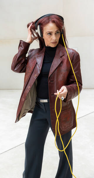 Photo of a woman wearing headphones in a brown leather jacket