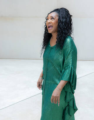 Photo of a woman in a green dress standing in a pale room