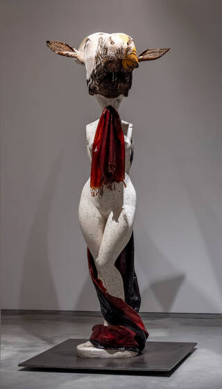 Photograph of a sculpture featuring a human form with large cow skeleton head