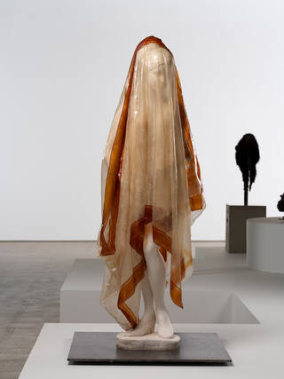 Sculpture of a woman wearing a long shiny, transparent veil over her head