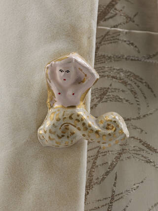 Detail of a ceramic button in the shape of a mermaid