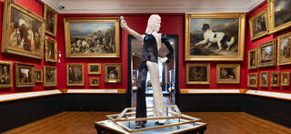 Black and white costume on a white stage in a room full of paintings with red walls